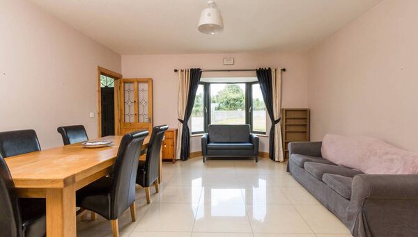 The dining room area with tiled flooring and a large bay window.