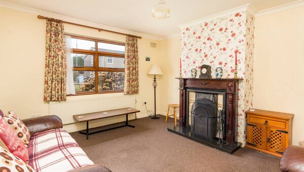 The living room has carpet flooring and an open fireplace. 