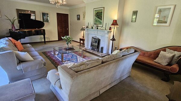 The spacious living room has an open fire and bay window.