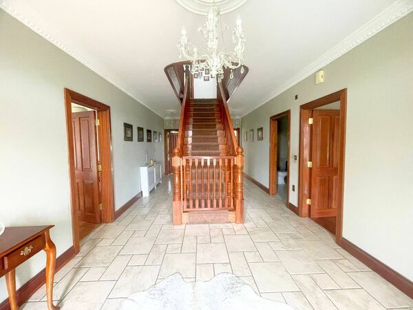 The large hallway features a sweeping staircase to the first floor.