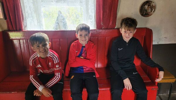 Nine generations on Daragh, Dylan and Shane sit on the red settle bed where their great grandmother Mollie and great aunt Helena O'Brien slept each night.