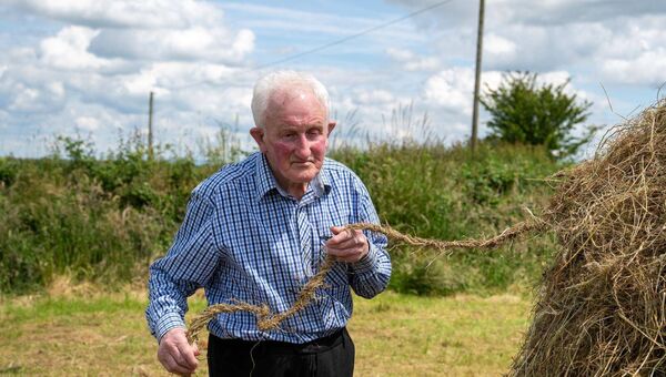 After the rope is prepared it is carefully drawn around the completed cock of hay. Pic: Breda Durr After the rope is prepared it is carefully drawn around the completed cock of hay. Pic: Breda Durr