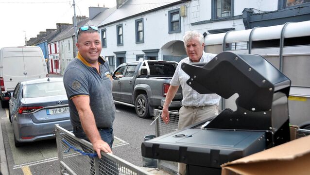 <p>Liam Scahill, Scahills of Castlerea helping Donal Dowd load his new barbecue. </p>